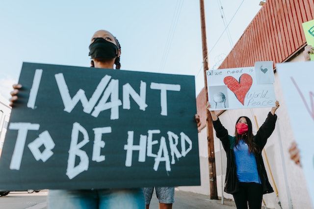 a woman holding board with i want to heard text and a woman holding world peace poster image