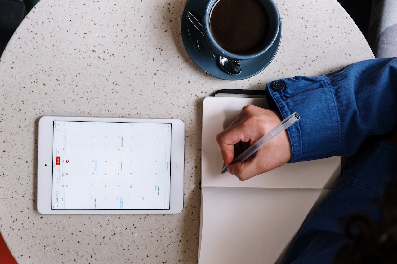 man using tablet and writing in a notebook image