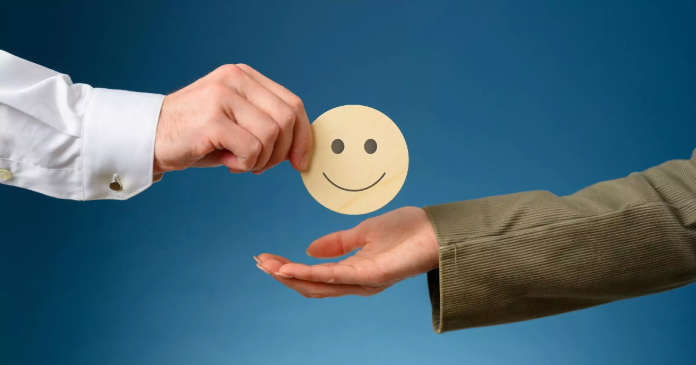 man handing paper cut round smiley to a woman