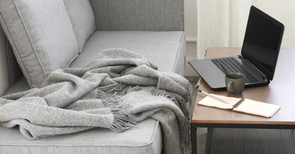 laptop, notepad and mug on a table near grey sofa image