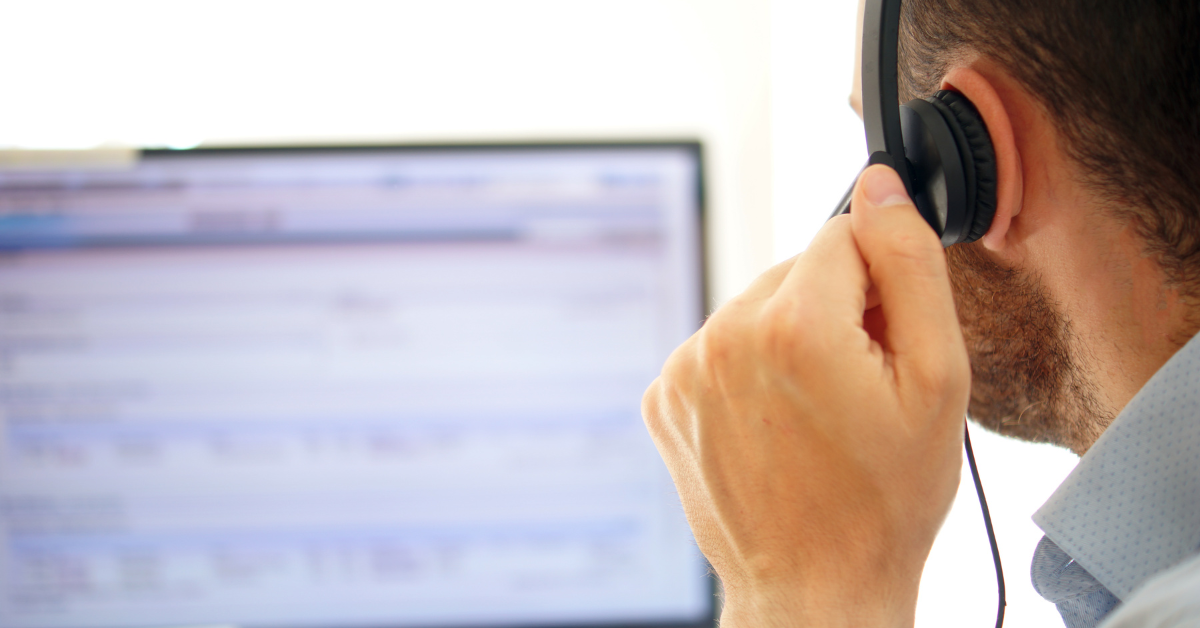 man receiving call through headphone and looking at computer screen image